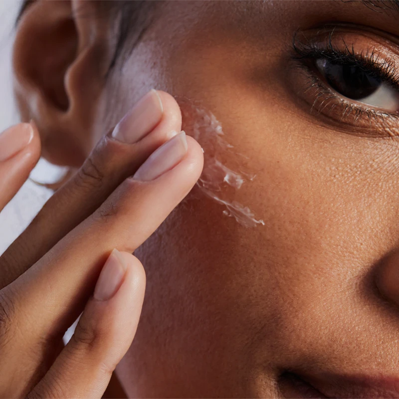 In the picture you can see a close-up shot of a person applying a cream to her face. (photo)