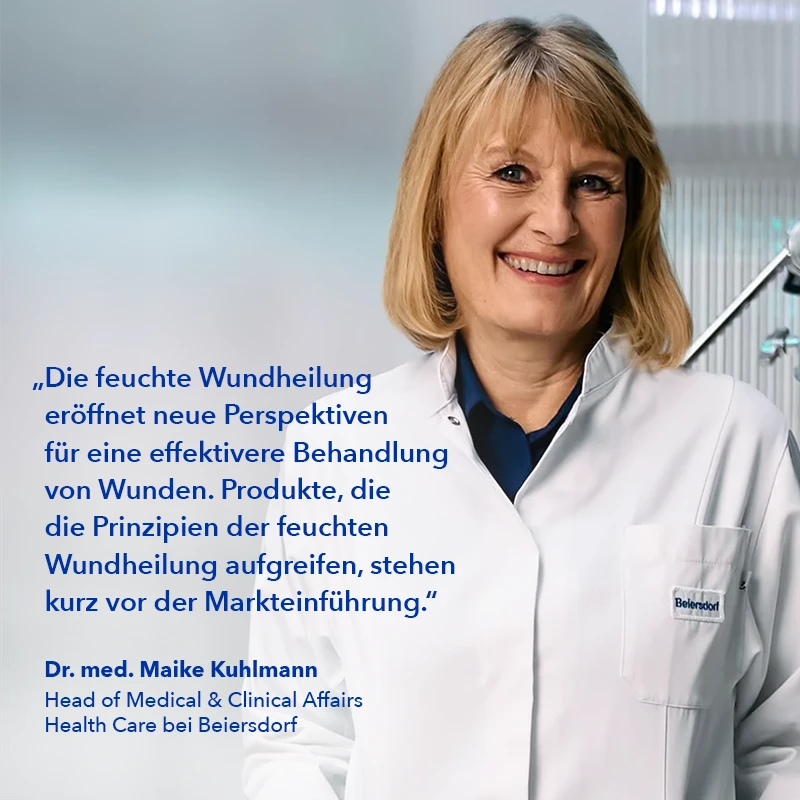 Auf dem Bild trägt eine Frau einen weißen Laborkittel und lächelt, während sie für ein Foto posiert. Sie scheint eine medizinische Fachkraft zu sein, möglicherweise eine Ärztin, da sie einen Laborkittel trägt und vor einer Kamera steht. Die Frau scheint gut gelaunt zu sein und genießt den Moment.